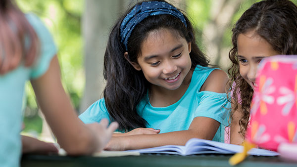 2 young girls reading in front of a tutor.